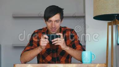 年轻人拿着智能手机玩手机游戏坐在家里的桌子旁，快乐的年轻人使用社交媒体应用程序工作学习